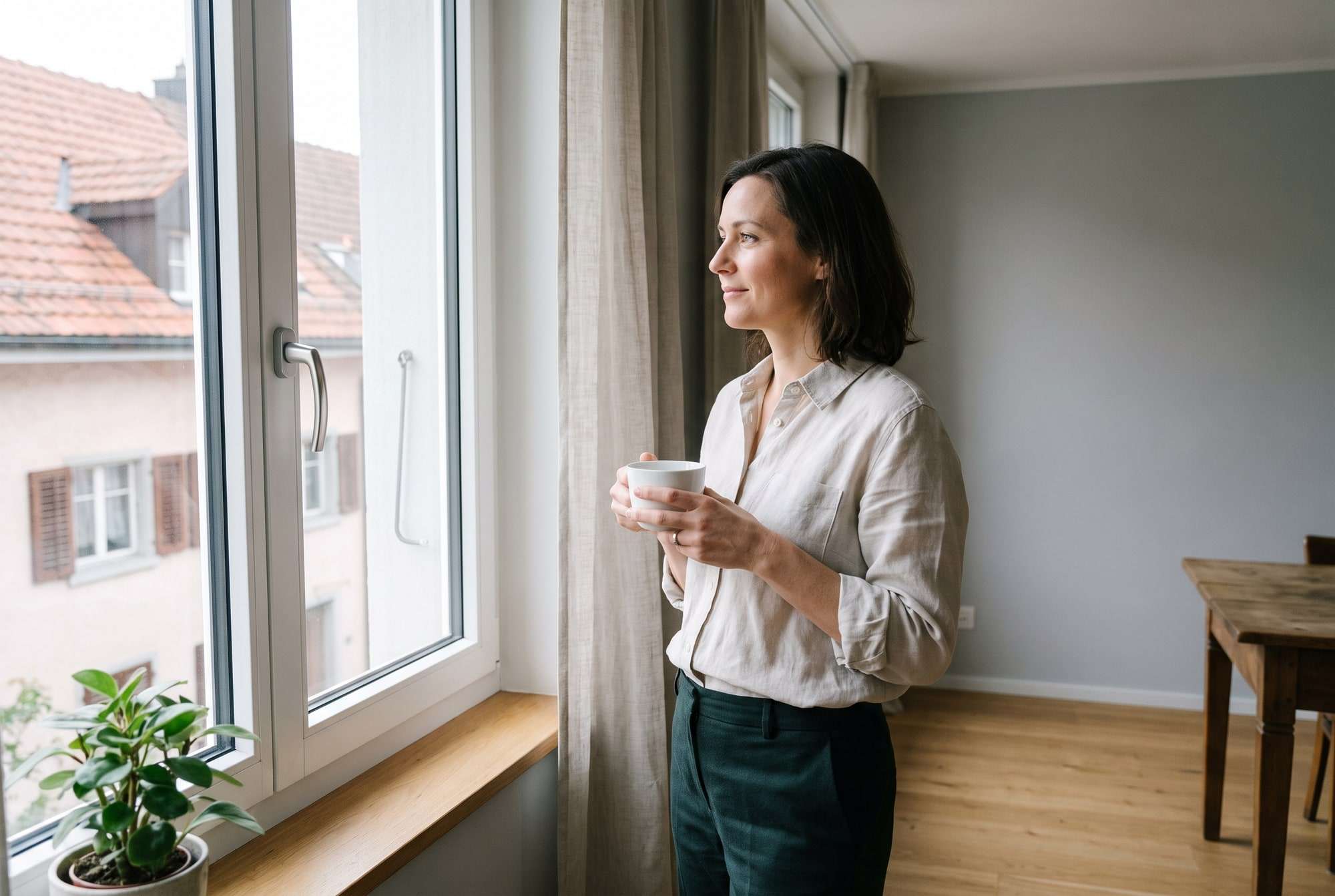 Frau mit Tasse am hellen Fenster