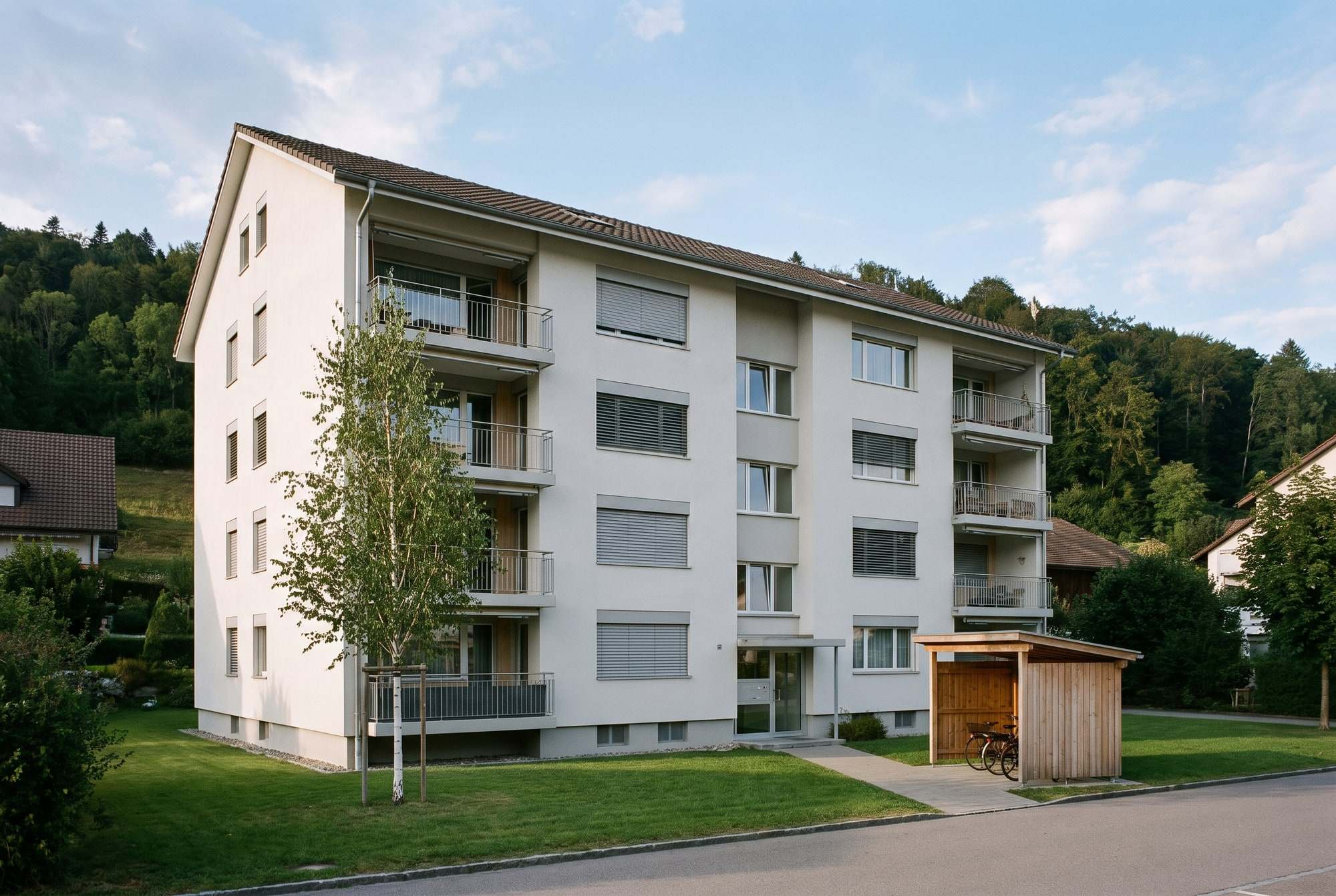 Mehrfamilienhaus mit Balkonen und Rasen am Waldrand