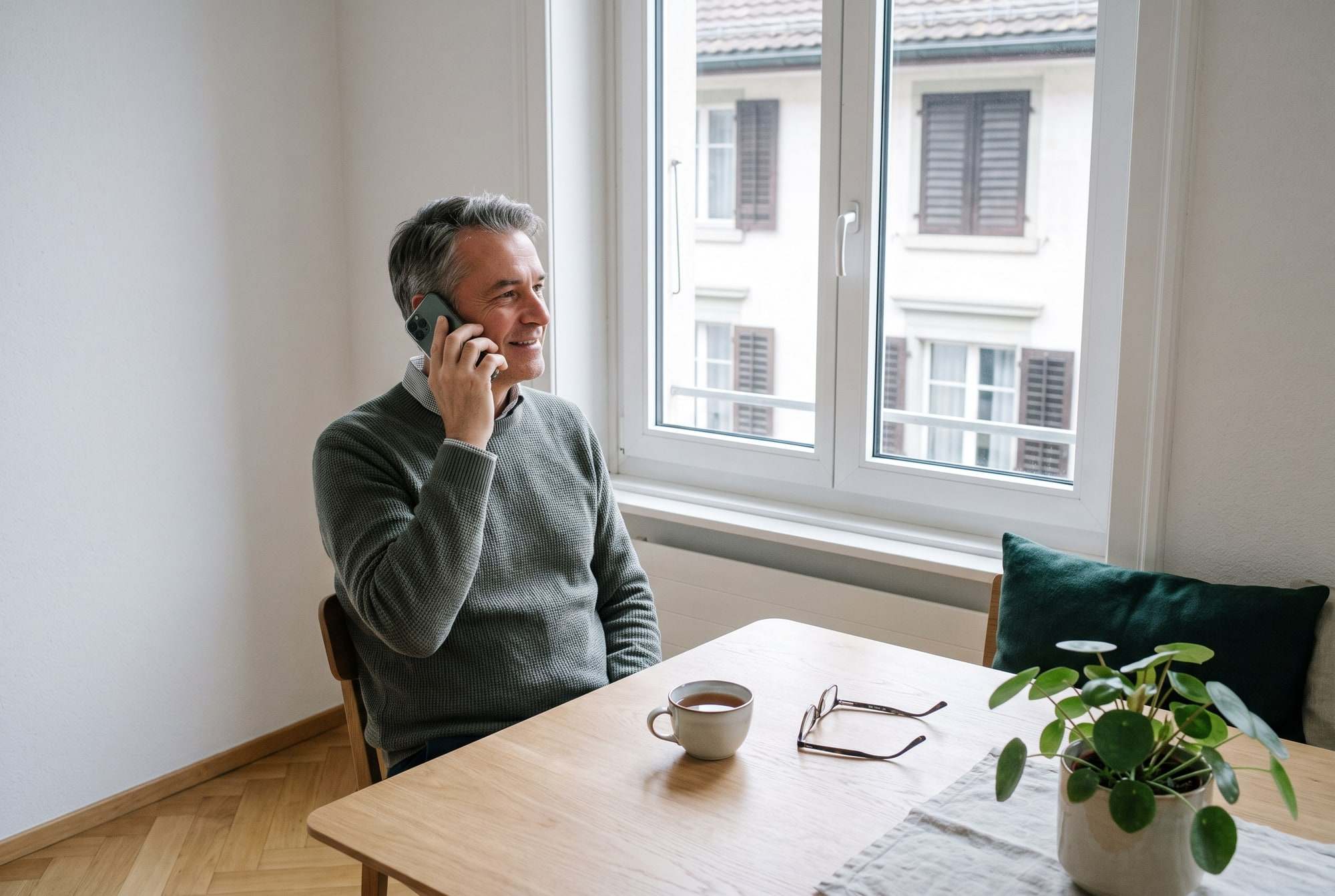 Mann telefoniert ruhig am Esstisch zu Hause